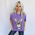 Woman wearing a purple t-shirt with a bunny graphic and glasses on a plain background