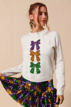 Ivory Mardi Gras sweater with sequin embellishments and decorative bow ribbons in purple, gold, and green, knit fabric, crew neckline, long sleeves, relaxed fit