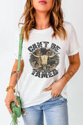 White western graphic tee with a “Can’t Be Tamed” skull leaned against an old barn. Neutral, bold, and perfect for denim, boots, and layered country outfits.