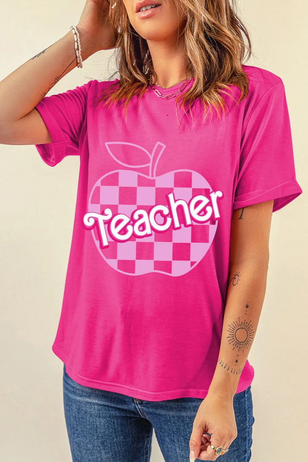 Pink teacher graphic tee with a checkered apple design in light and dark pink, plus “Teacher” in a Barbie-style font. Soft, cute, comfy, and perfect for school days.