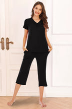 Solid black 2-piece lounge outfit with a V-neck short sleeve top and capri pants. Soft, opaque, stretchy rayon knit with pockets and a relaxed fit.