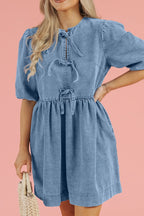 Above-knee denim dress with balloon sleeves, elastic cuffs, and a gathered waist. Soft gathered fit with a stitched bow accent and a flattering cinched silhouette.