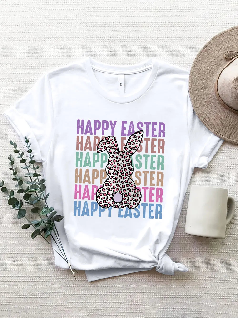 Happy Easter graphic tee with leopard bunny and pastel lettering printed on a white shirt from Soaring Eagle Boutique.