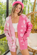 Pink and ivory color-block knit cardigan with heart pattern and side pockets. Soft slight-stretch fabric, open V-neck fit, cozy boutique layering sweater.
