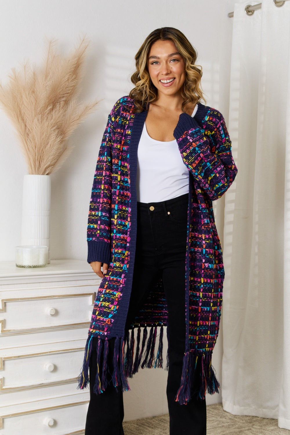 Black open-front cardigan with fringe hem and vibrant multicolor yarn woven throughout. Soft, stretchy knit, relaxed everyday fit.
