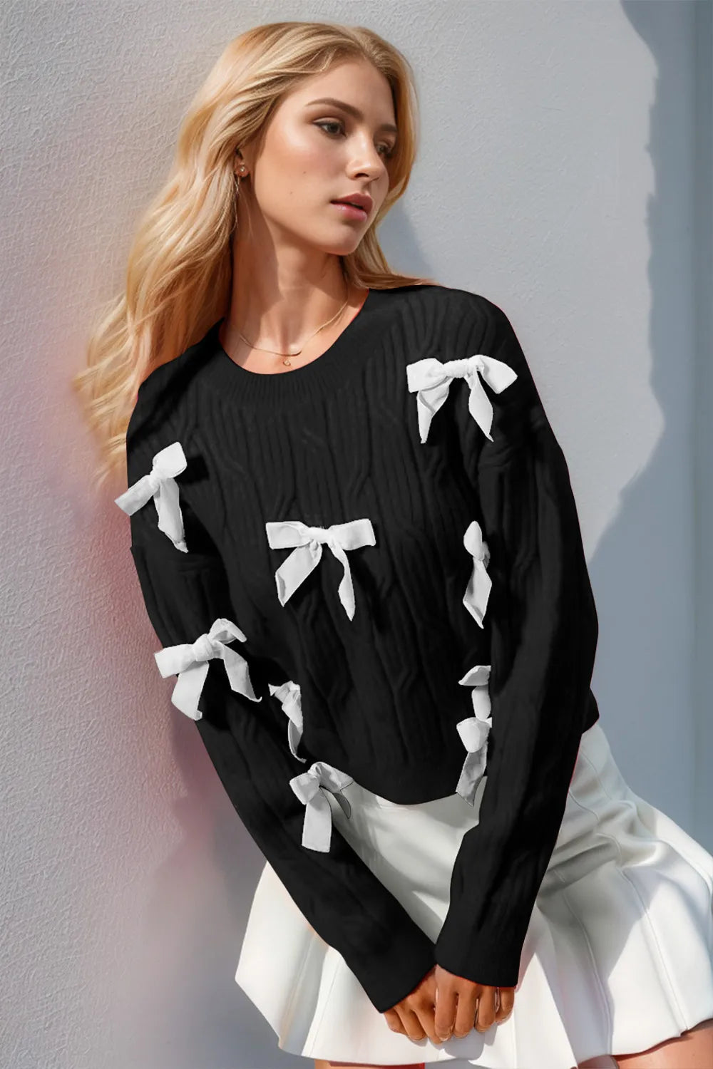 Women’s black knit sweater with white stitched bow details, long sleeves, soft casual-retro layering top for everyday cozy outfits.