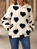 Fuzzy sherpa hoodie in off-white with black heart-shaped pockets. Long sleeves, dropped shoulder pullover fit, soft cozy casual look.