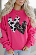 Pink sweatshirt with cowprint heart patch and black sequin heart stitched on. Opaque fabric, relaxed pullover fit, long sleeves, casual outfit favorite.